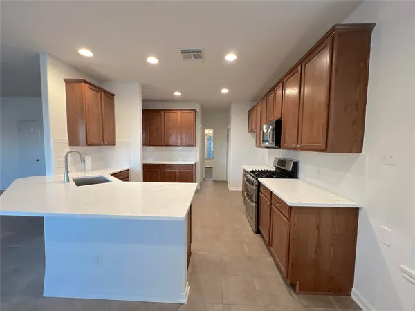 a large kitchen with stainless steel appliances kitchen island granite countertop a sink a stove and a refrigerator