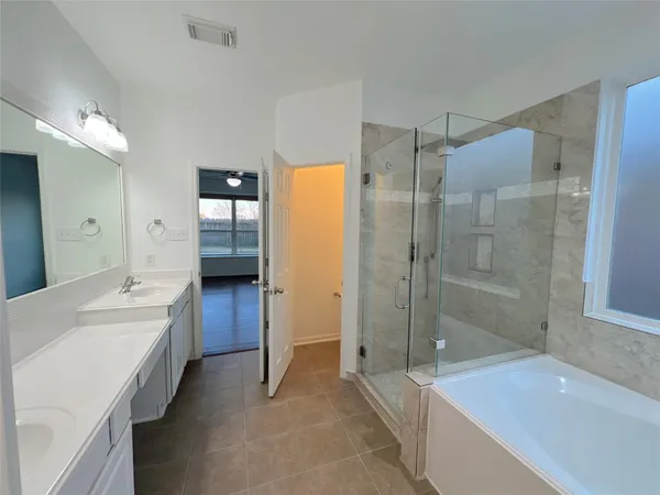 a spacious bathroom with a tub sink shower and mirror
