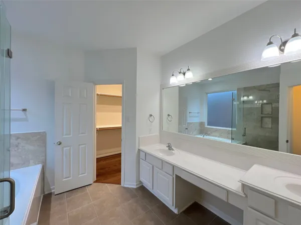 a bathroom with a double vanity sink a large mirror and a bathtub