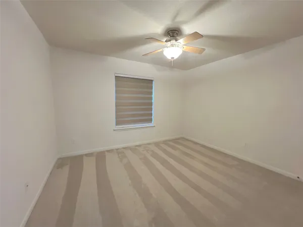 a view of an empty room with a chandelier fan