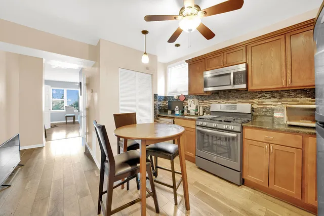 a kitchen with stainless steel appliances kitchen island granite countertop a stove top oven a sink a dining table and chairs with wooden floor