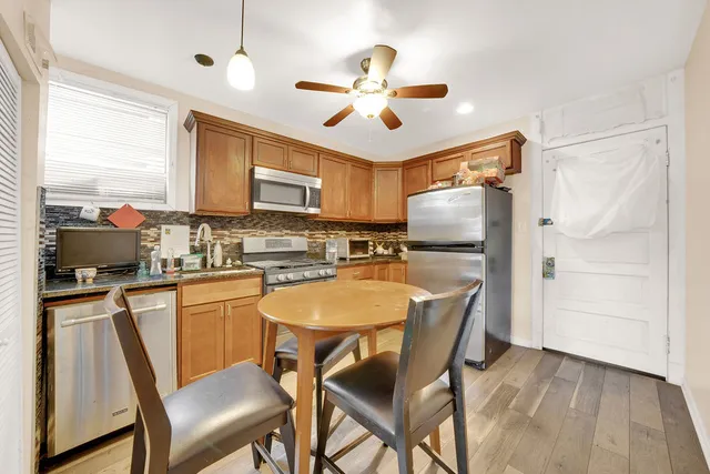 a kitchen with stainless steel appliances granite countertop a stove a refrigerator a sink a stove and white cabinets with wooden floor