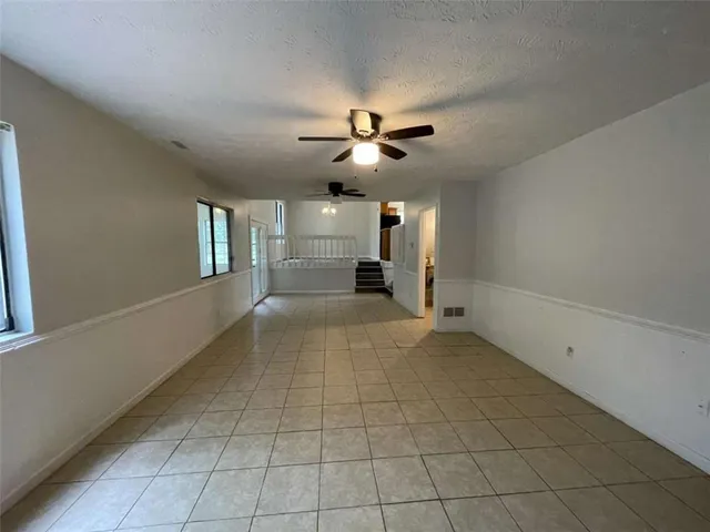 a view of a livingroom with a fireplace a chandelier fan and windows
