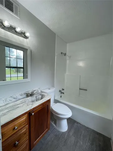 a bathroom with a granite countertop sink toilet and shower