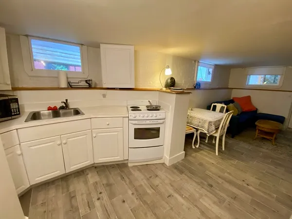 a kitchen with stainless steel appliances kitchen island granite countertop a refrigerator a stove a sink dishwasher and white cabinets with wooden floor