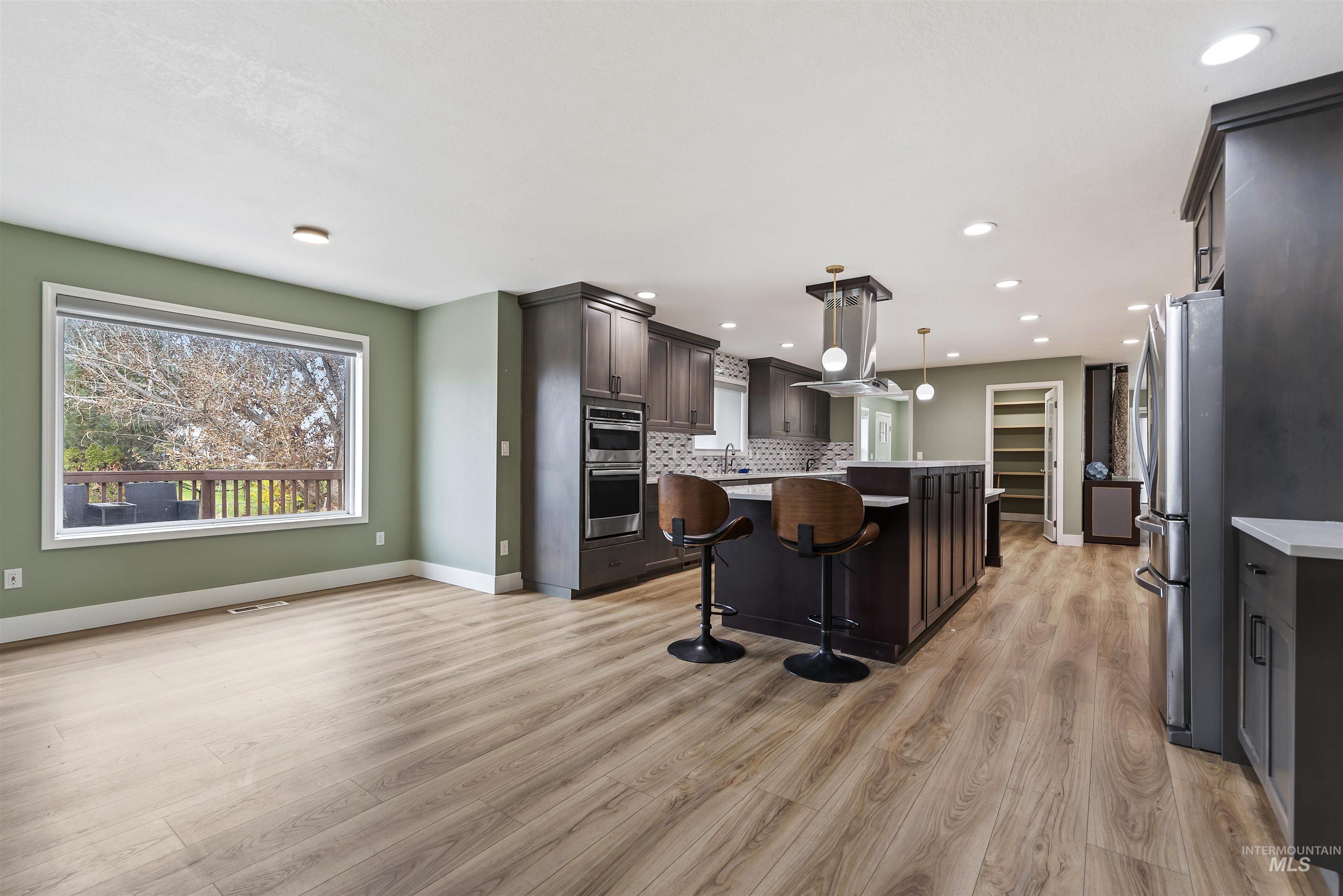 3160 East Springwood Drive Meridian, ID 83642 - Photo 12 of 41 Kitchen with a kitchen bar, a kitchen island, stainless steel appliances, dark brown cabinetry, and hanging light fixtures