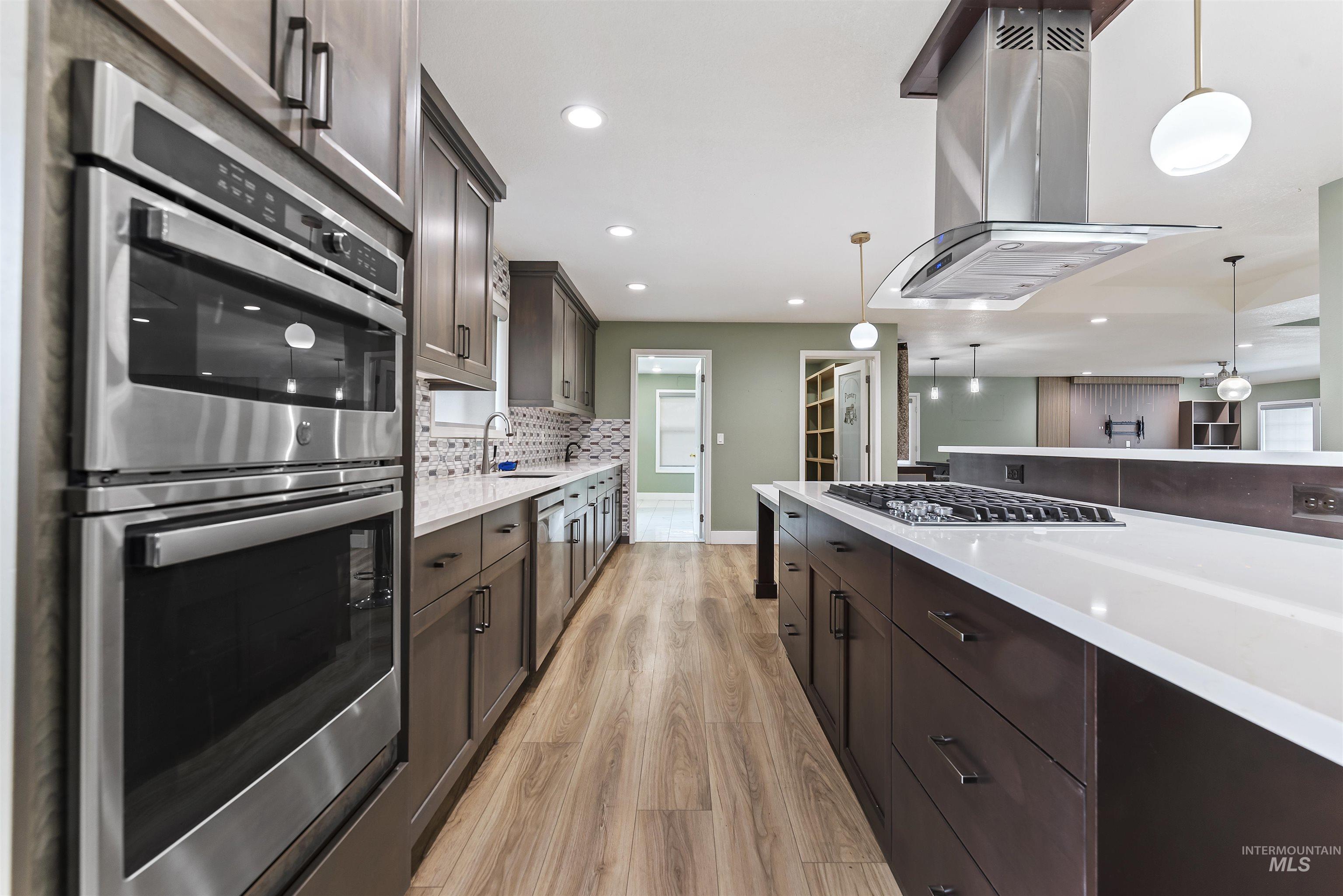 3160 East Springwood Drive Meridian, ID 83642 - Photo 13 of 41 Kitchen featuring appliances with stainless steel finishes, island range hood, dark brown cabinets, decorative light fixtures, and recessed lighting