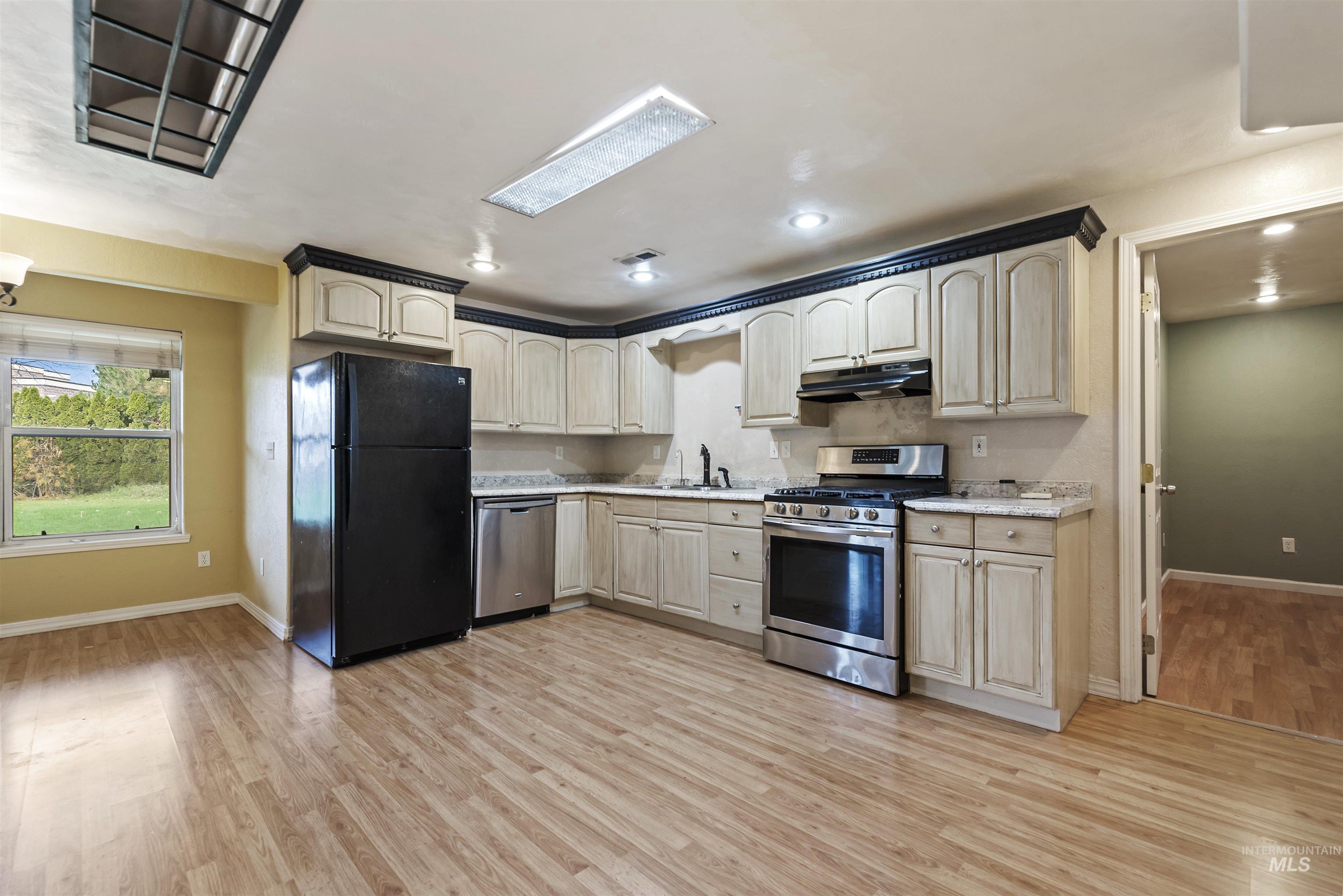 3160 East Springwood Drive Meridian, ID 83642 - Photo 15 of 41 Kitchen with appliances with stainless steel finishes, light countertops, light wood-style flooring, under cabinet range hood, and recessed lighting