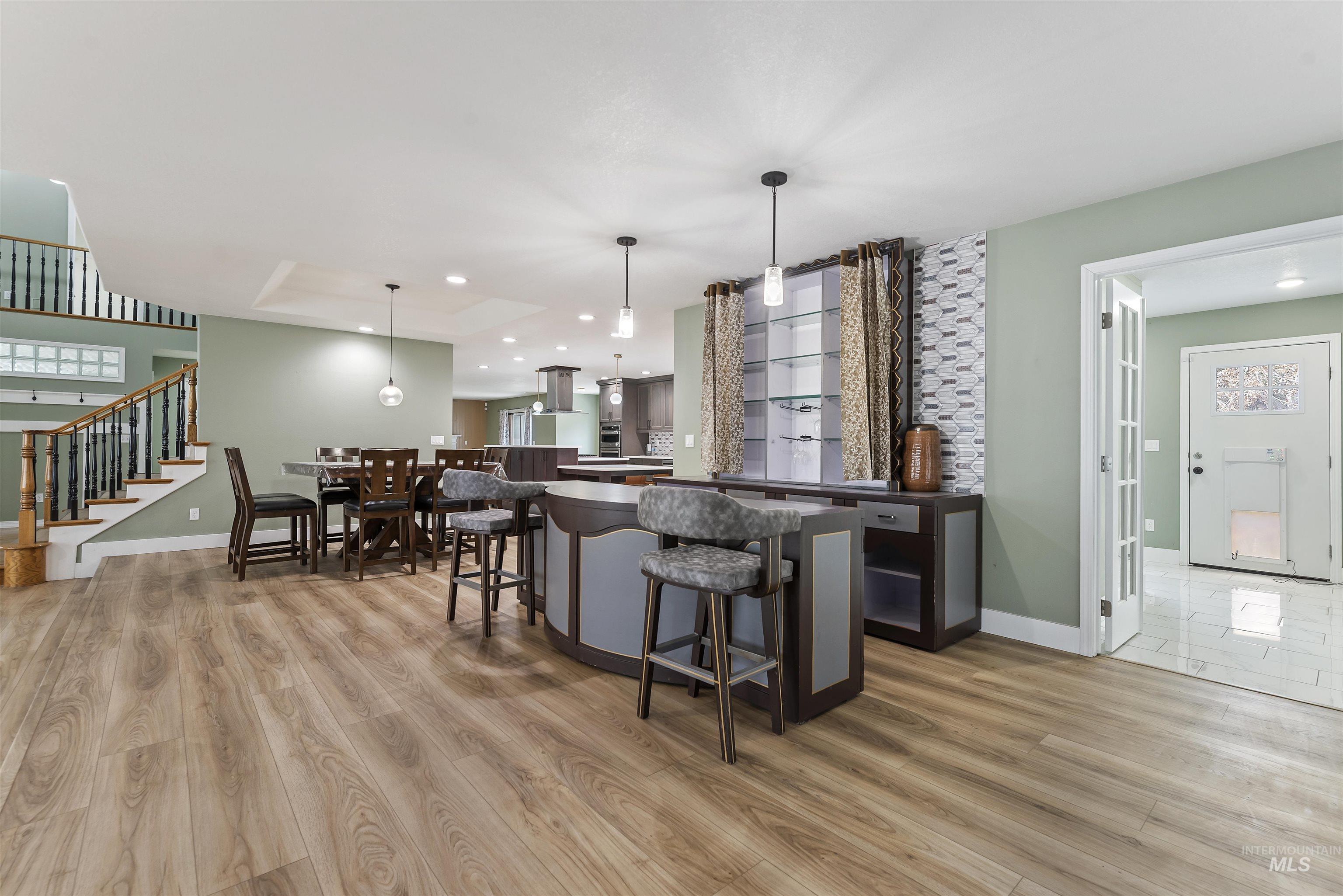 3160 East Springwood Drive Meridian, ID 83642 - Photo 16 of 41 Bar area featuring dark countertops, hanging light fixtures, a tray ceiling, stairway, and light wood-type flooring