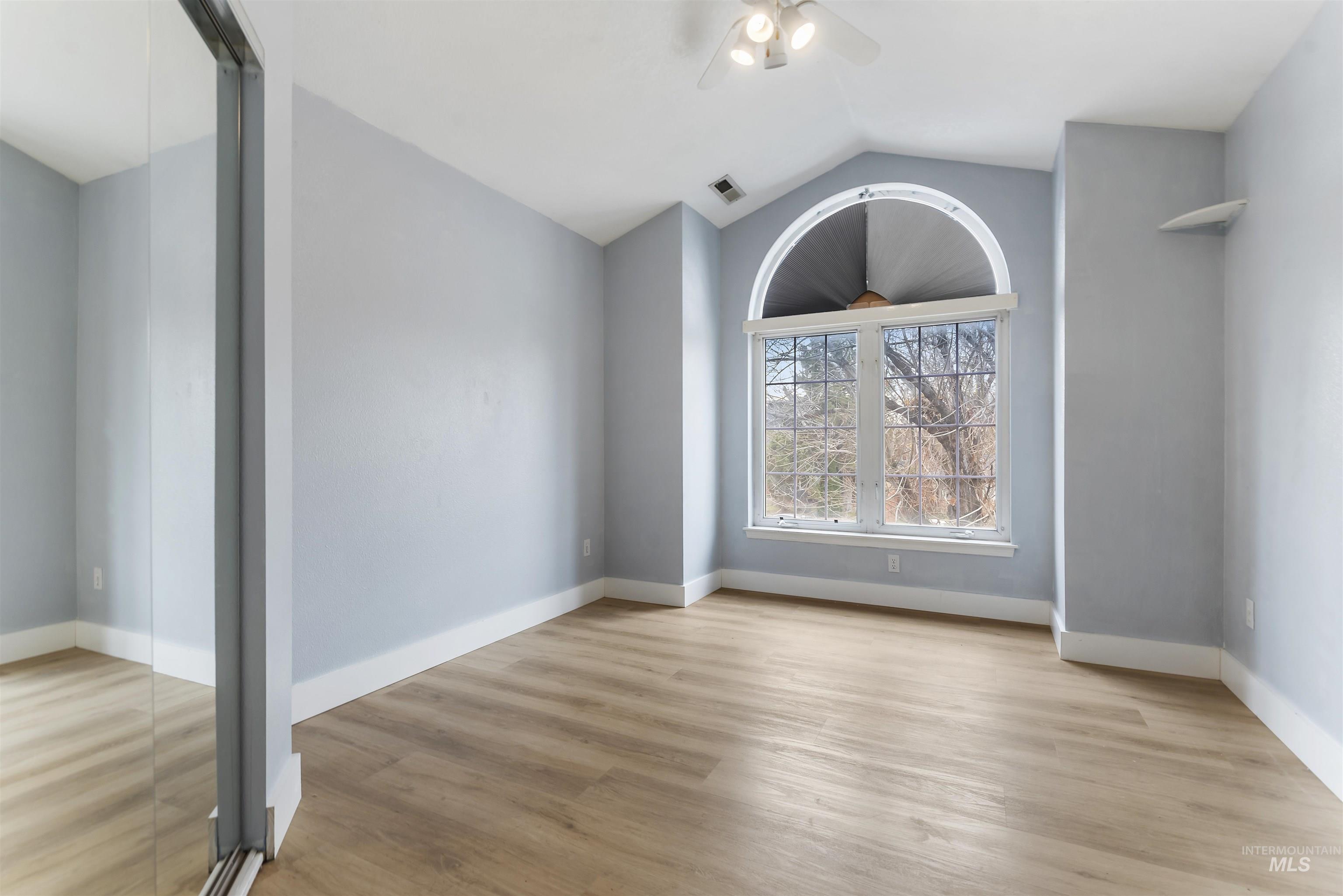 3160 East Springwood Drive Meridian, ID 83642 - Photo 21 of 41 Empty room featuring vaulted ceiling, light wood finished floors, and ceiling fan