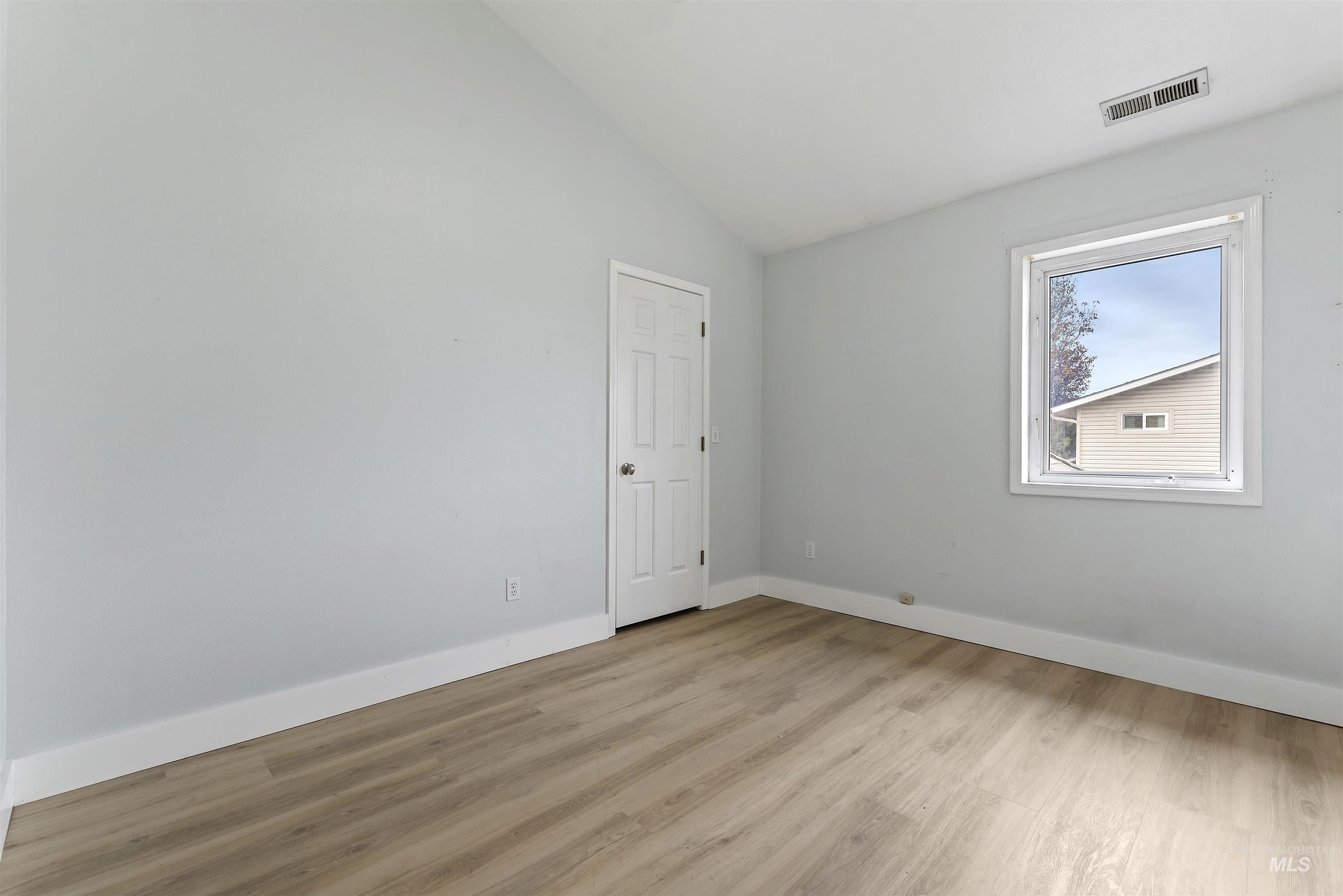 3160 East Springwood Drive Meridian, ID 83642 - Photo 22 of 41 Empty room with vaulted ceiling and light wood-style floors