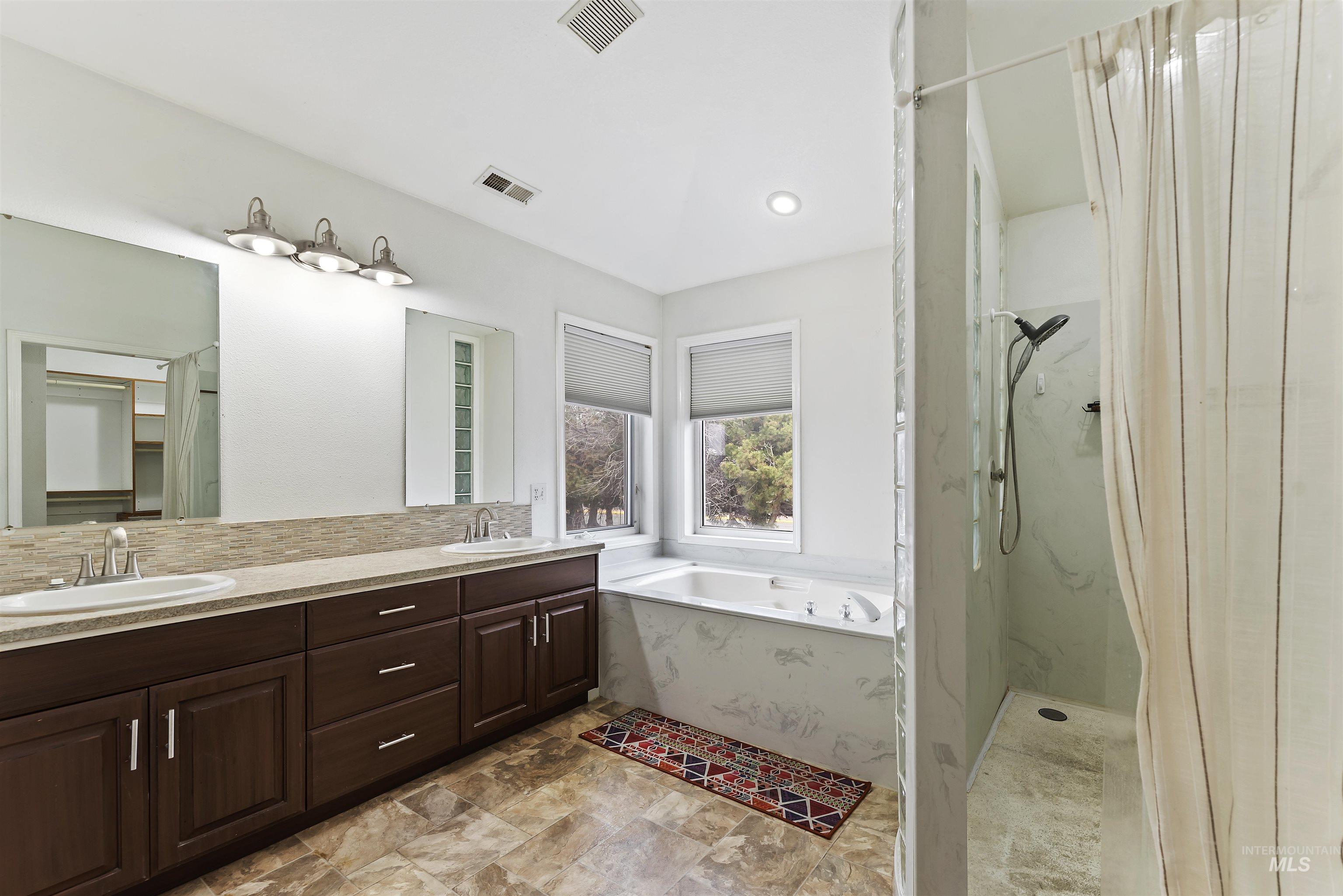 3160 East Springwood Drive Meridian, ID 83642 - Photo 23 of 41 Full bathroom with a marble finish shower, double vanity, a bath, decorative backsplash, and stone finish floors