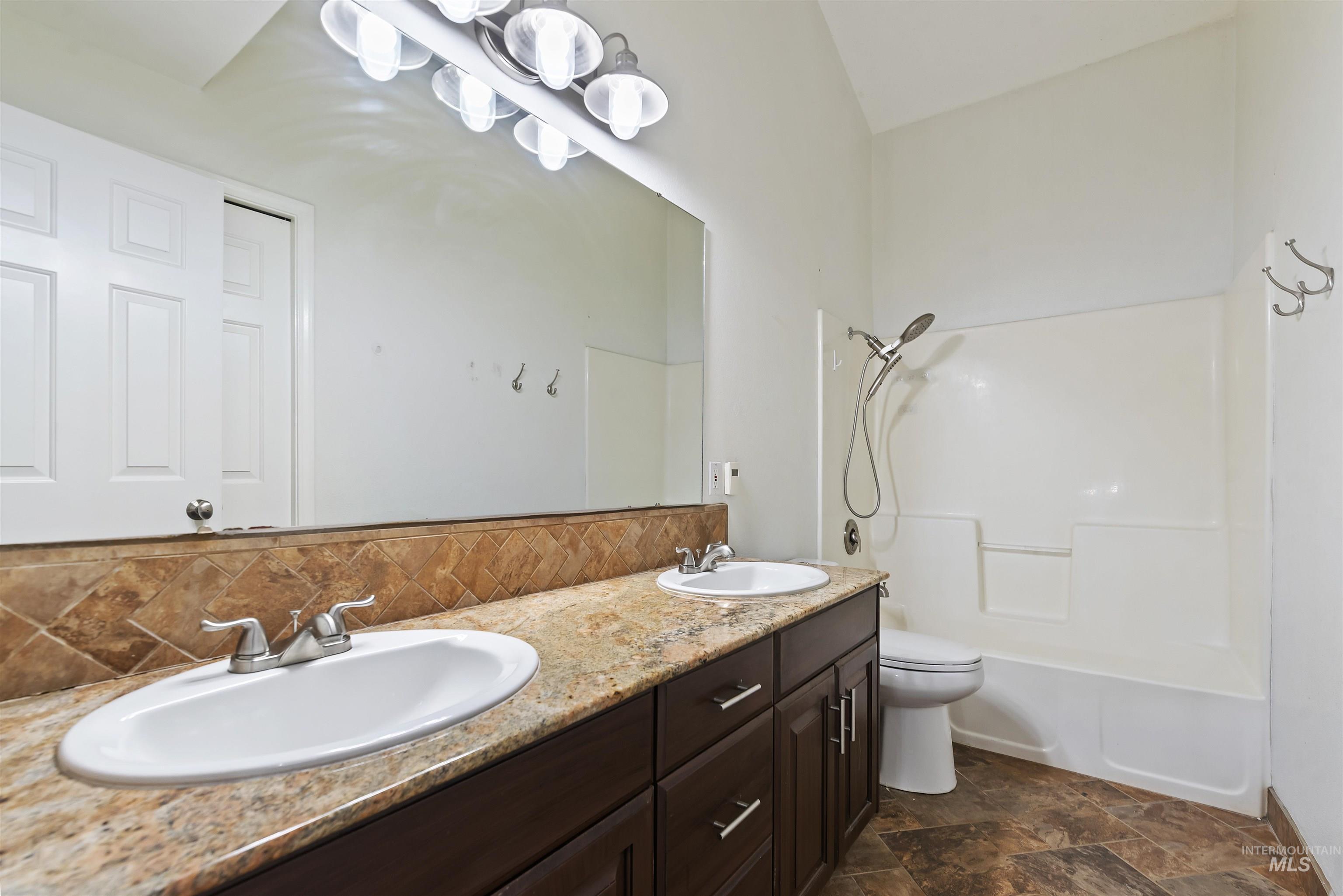 3160 East Springwood Drive Meridian, ID 83642 - Photo 25 of 41 Full bathroom featuring double vanity, shower / washtub combination, backsplash, and stone finish floors