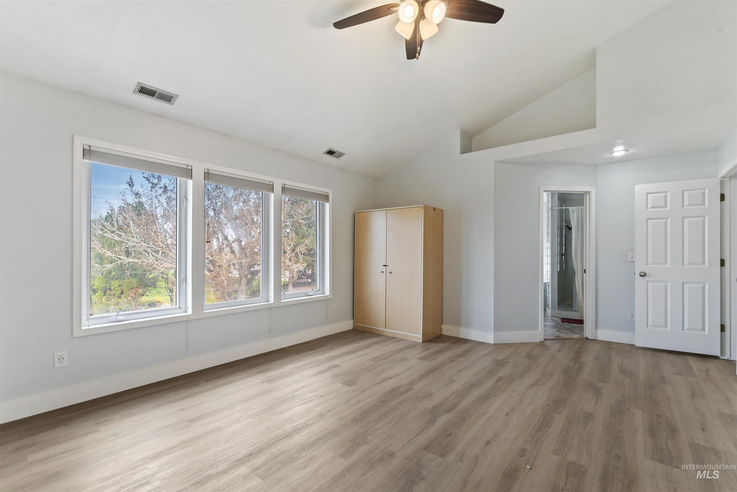 3160 East Springwood Drive Meridian, ID 83642 - Photo 34 of 41 Unfurnished bedroom with light wood finished floors, multiple windows, ceiling fan, ensuite bathroom, and high vaulted ceiling