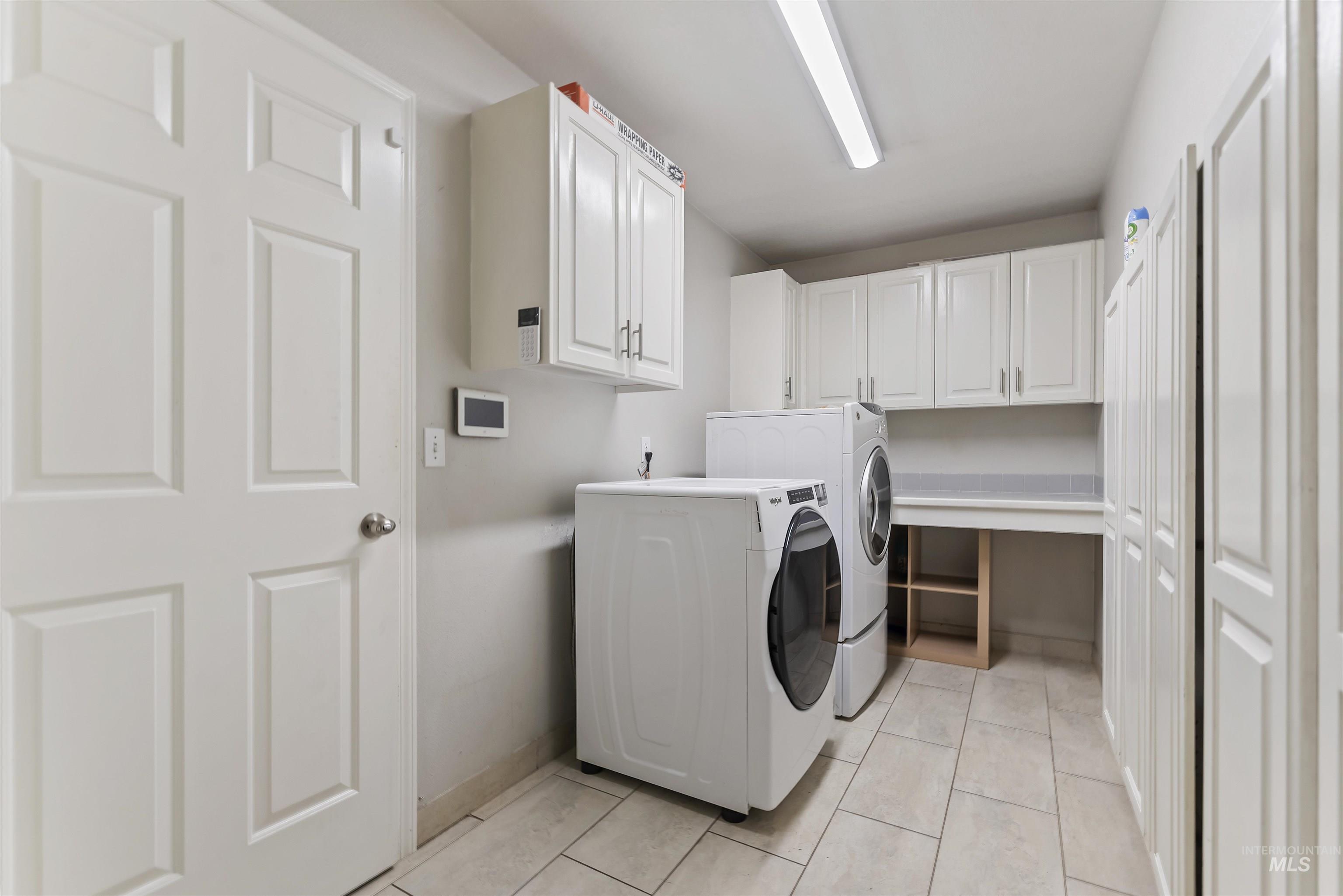 3160 East Springwood Drive Meridian, ID 83642 - Photo 35 of 41 Laundry area featuring cabinet space, washer and clothes dryer, and light tile patterned floors