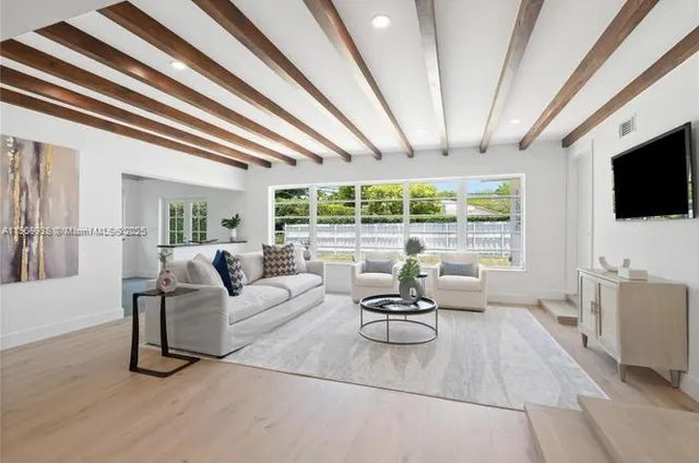 a living room with furniture a flat screen tv and a large window