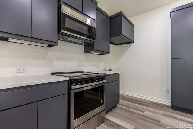 a kitchen with stainless steel appliances a stove a microwave and wooden floors