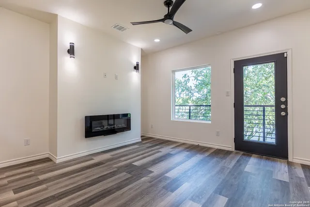 a view of an empty room with wooden floor fireplace and a window
