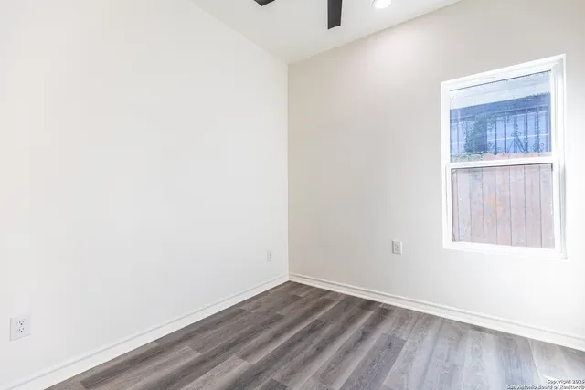 a view of an empty room with wooden floor and a window