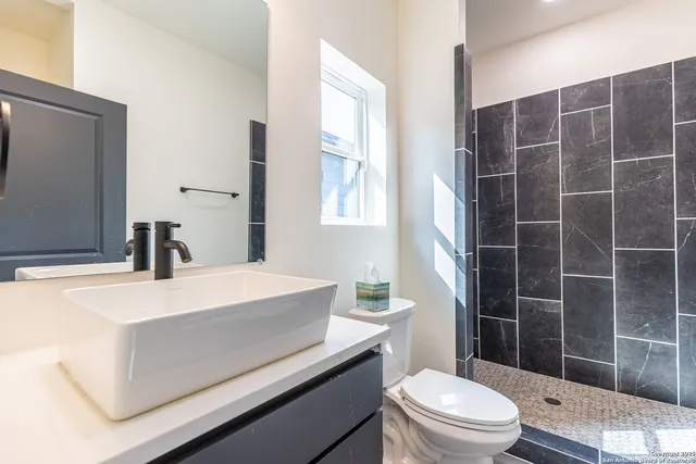 a bathroom with a sink a toilet a mirror and shower