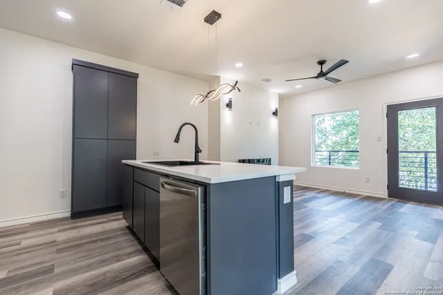 a kitchen with a sink chandelier and wooden floor