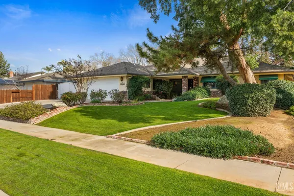 a front view of a house with a yard and potted plants