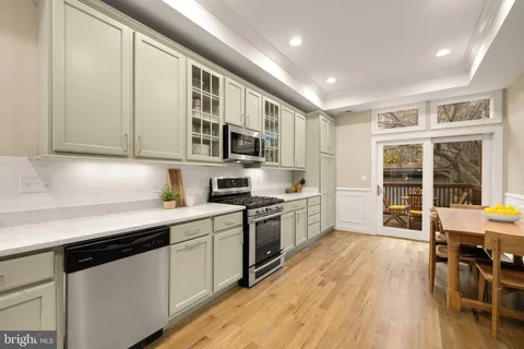 a kitchen with stainless steel appliances granite countertop white cabinets a sink dishwasher a stove and a refrigerator with wooden floor