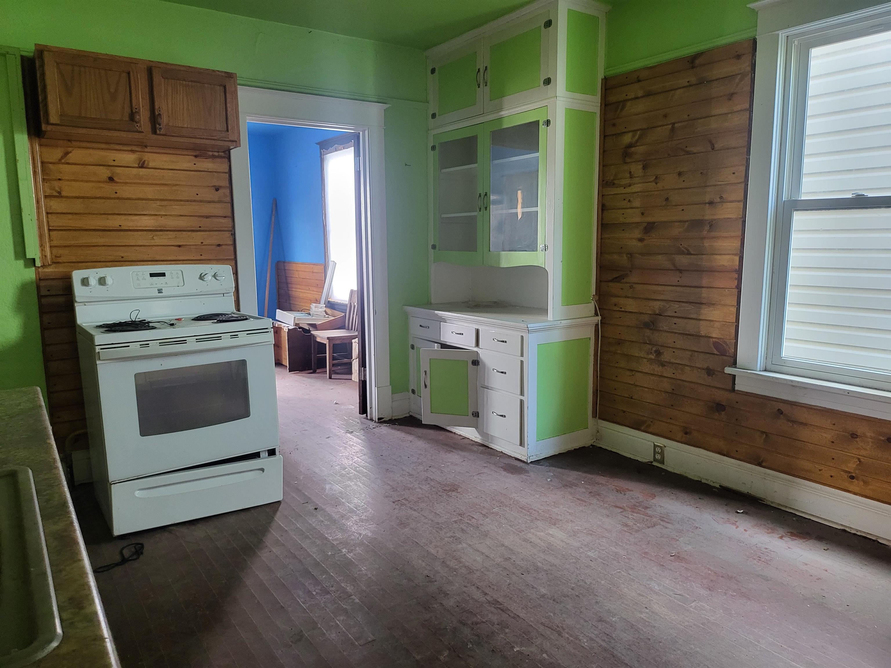 119 8th Street South Virginia, MN 55792 - Photo 6 of 18 Kitchen featuring white electric range oven, dark wood finished floors, light countertops, and wooden walls