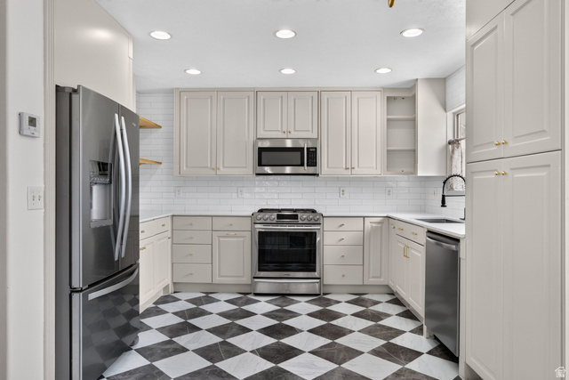 2223 North Pointe Meadow Loop Lehi, UT 84048 - Photo 14 of 56 Kitchen featuring checkerboard flooring, white subway tile backsplash, light-toned cabinetry with gold-toned hardware, stainless steel appliances, and recessed lighting
