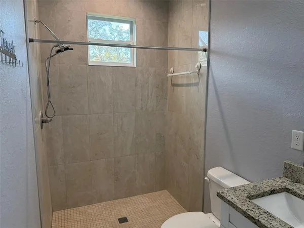 a bathroom with a granite countertop sink toilet and shower