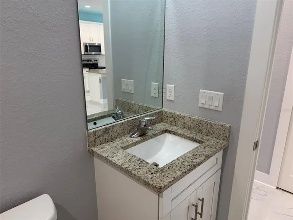 a bathroom with a granite countertop sink and a toilet
