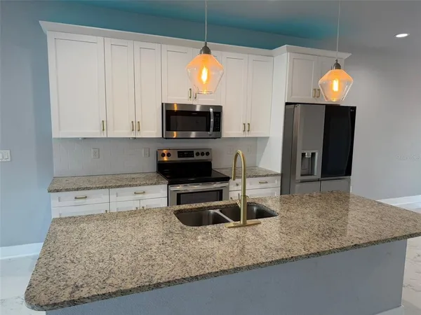 a kitchen with a sink a microwave and cabinets
