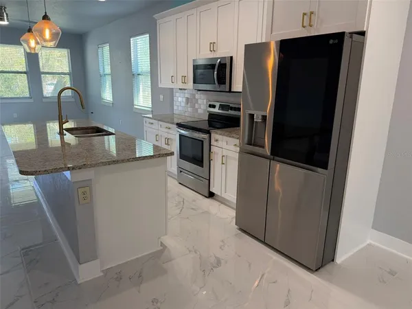 a kitchen with stainless steel appliances a refrigerator a sink a stove a microwave a counter top space and cabinets