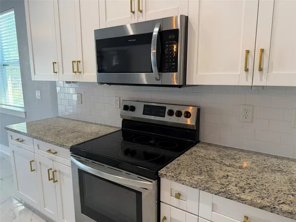 a kitchen with granite countertop white cabinets and black stainless steel appliances