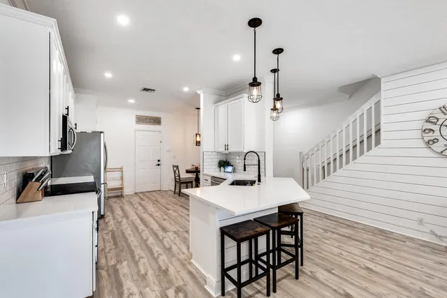 a kitchen with granite countertop a sink chairs and refrigerator
