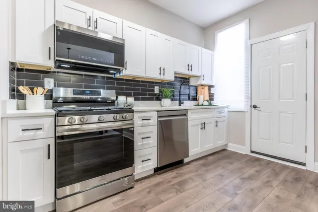 a kitchen with stainless steel appliances white cabinets and a stove top oven