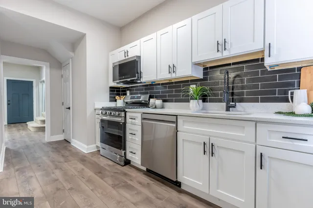 a kitchen with white cabinets stainless steel appliances and sink