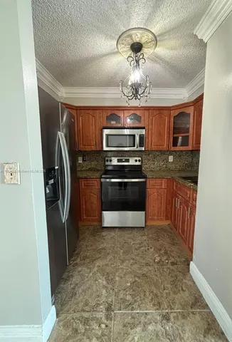 a kitchen with stainless steel appliances granite countertop a refrigerator a stove and a sink