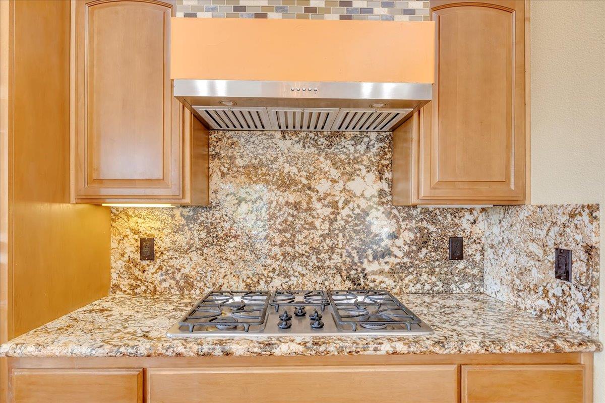 33 Aurora Lane Copperopolis, CA 95228 - Photo 17 of 46 kitchen featuring extractor fan, stainless steel gas cooktop, light stone countertops, light wood finish cabinetry, and tasteful backsplash