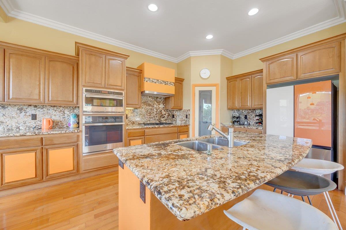 33 Aurora Lane Copperopolis, CA 95228 - Photo 18 of 46 kitchen featuring stainless steel appliances, light stone counters, light wood finished floors, crown molding, and a breakfast bar area