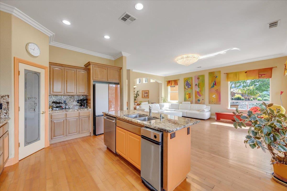 33 Aurora Lane Copperopolis, CA 95228 - Photo 45 of 46 kitchen with open floor plan, light stone countertops, ornamental molding, a center island with sink, and light wood-style flooring