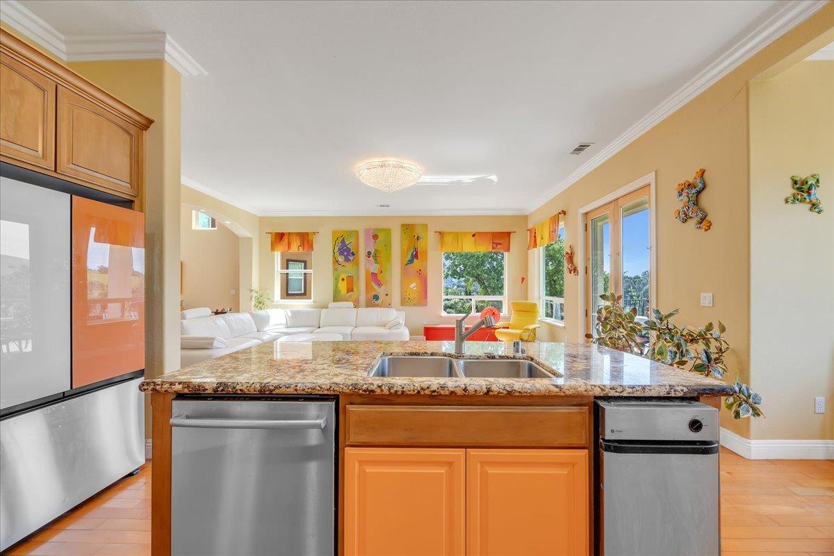 33 Aurora Lane Copperopolis, CA 95228 - Photo 46 of 46 kitchen featuring stainless steel appliances, open floor plan, an island with sink, light wood finished floors, and ornamental molding
