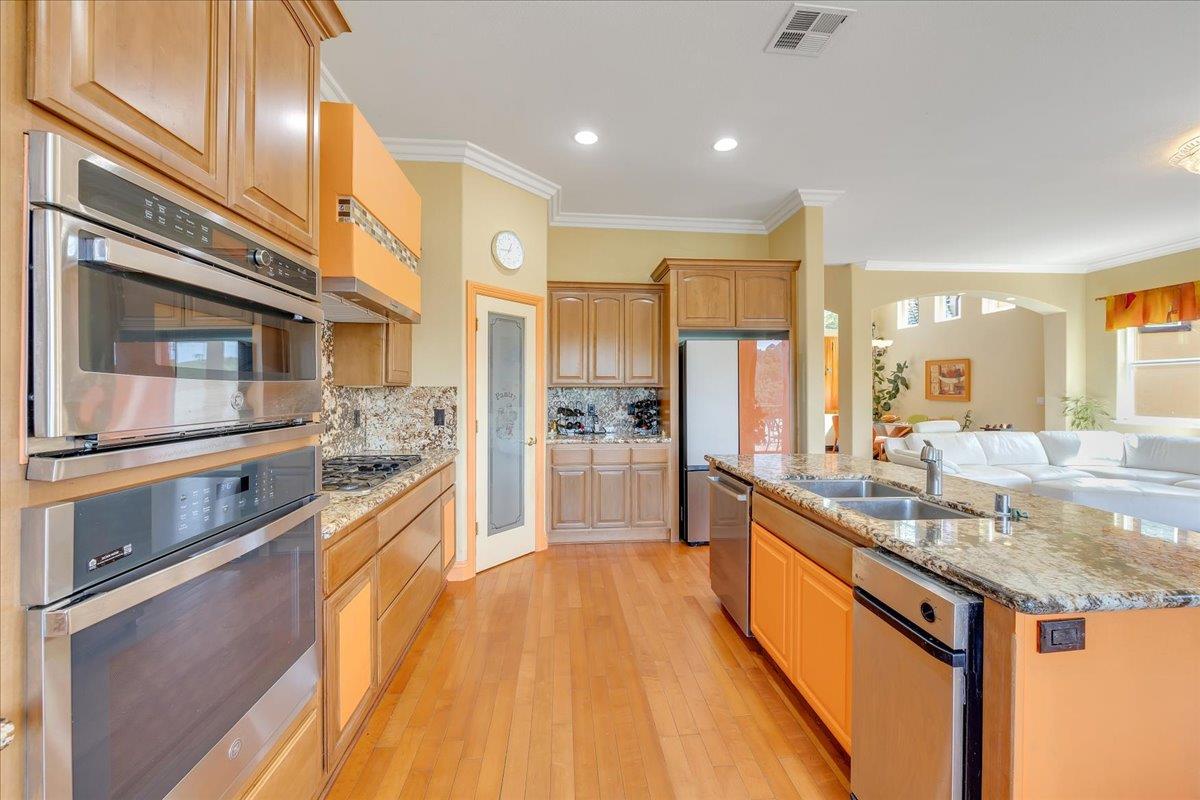 33 Aurora Lane Copperopolis, CA 95228 - Photo 19 of 46 kitchen featuring stainless steel appliances, a kitchen island with sink, light wood-type flooring, backsplash, and light stone counters