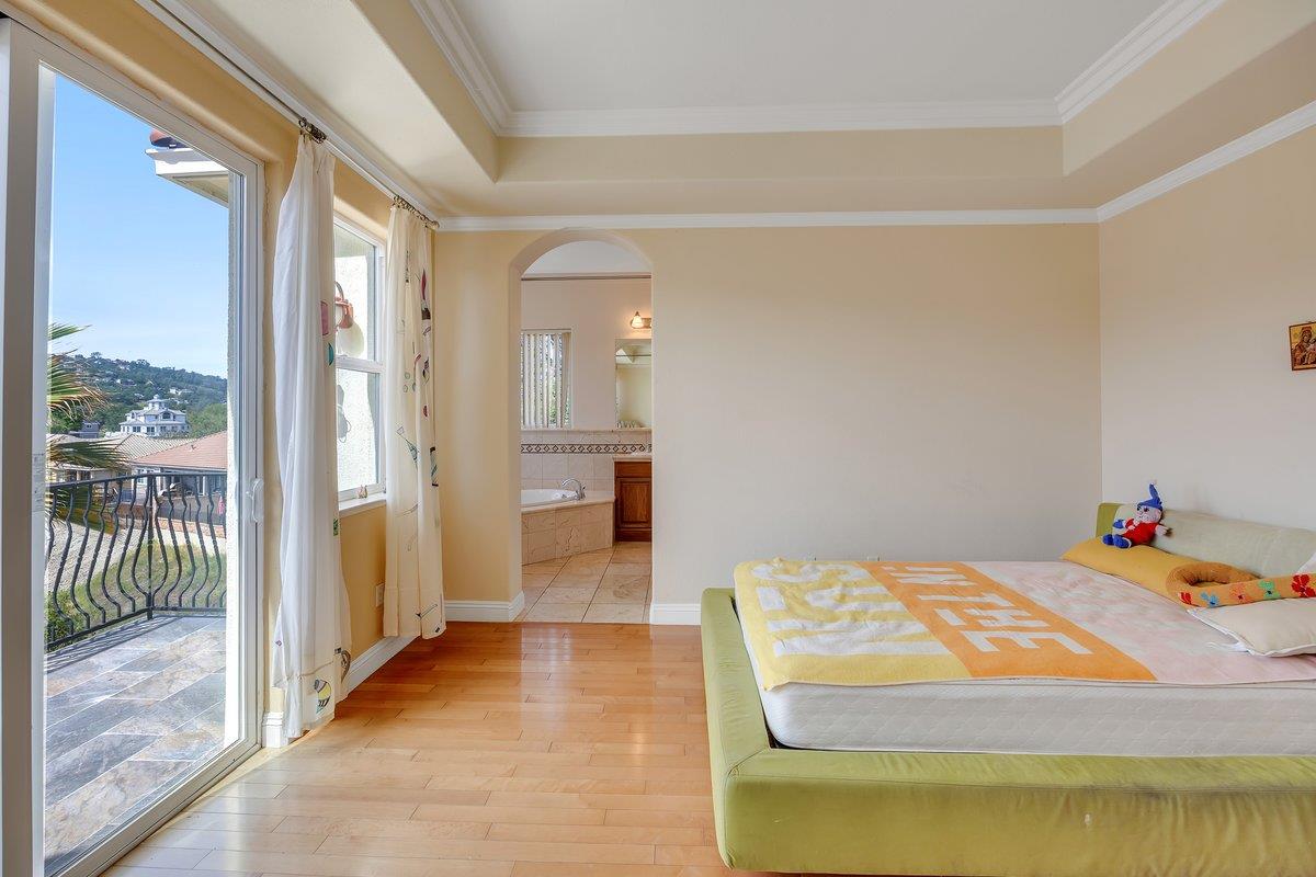 33 Aurora Lane Copperopolis, CA 95228 - Photo 22 of 46 bedroom featuring arched walkways, light wood-style flooring, access to outside, a tray ceiling, and crown molding