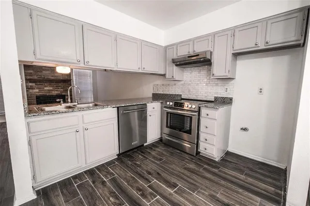 a kitchen with cabinets stainless steel appliances and wooden floor