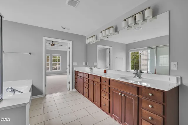 a spacious bathroom with a double vanity sink a mirror and a bathtub