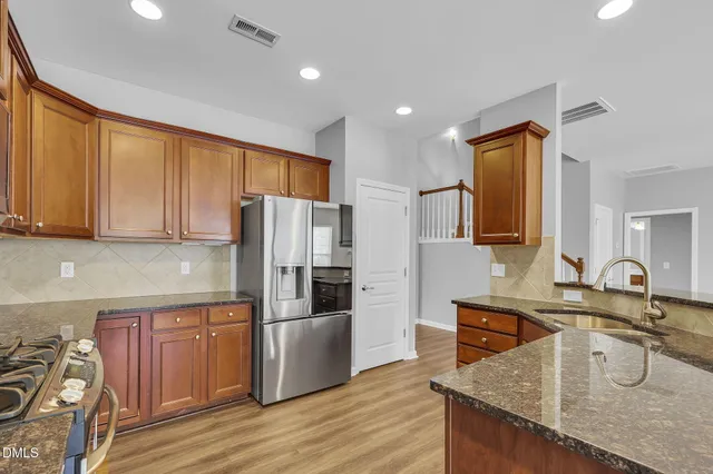 a kitchen with granite countertop a sink a counter top space stainless steel appliances and cabinets