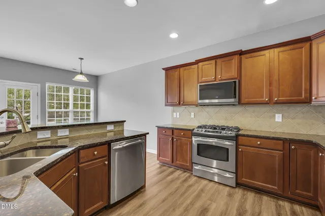 a kitchen with stainless steel appliances granite countertop a sink stove and microwave