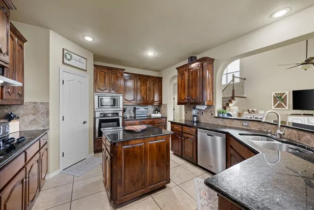 a kitchen with stainless steel appliances granite countertop a stove top oven a sink dishwasher a refrigerator and a oven