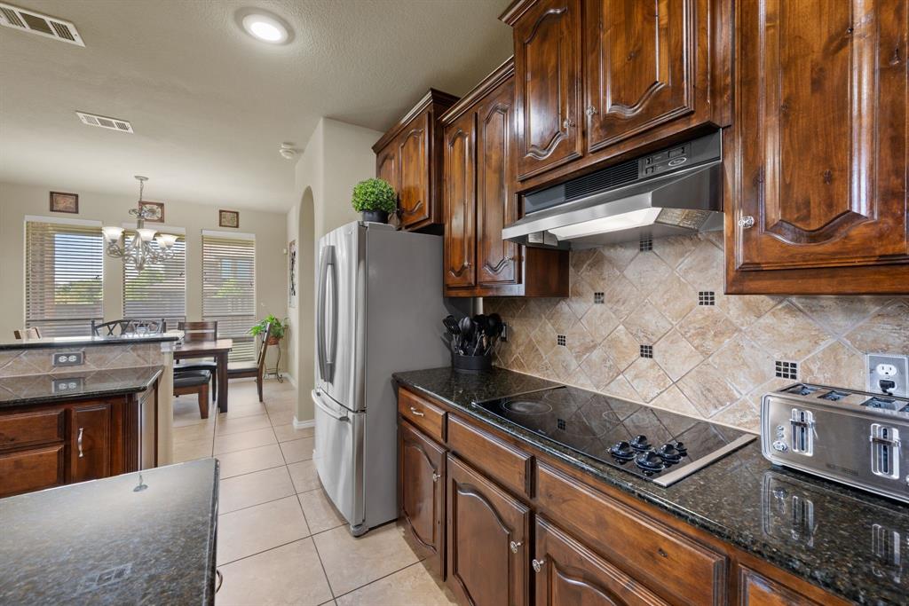 4172 Drexmore Road Fort Worth, TX 76244 - Photo 13 of 37 a kitchen with stainless steel appliances granite countertop a refrigerator a stove and a sink with wooden cabinets